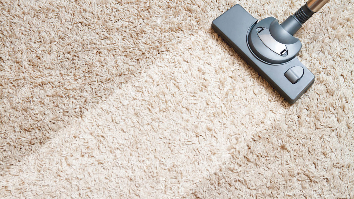 Vacuum cleaning a beige carpet.